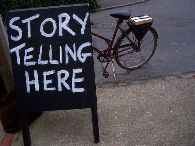 A bicycle is parked next to a sign that says story telling here