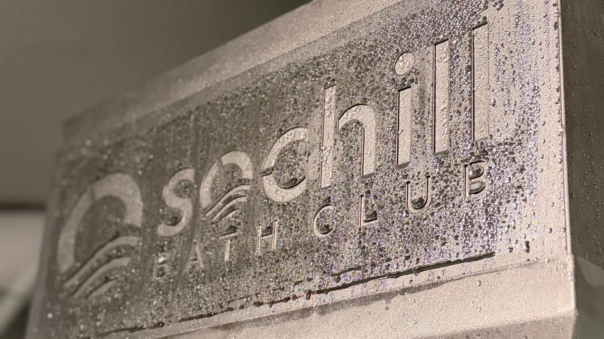 Woman submerged in ice bath, eyes closed, smiling, arms at sides. White ice surrounds her.
