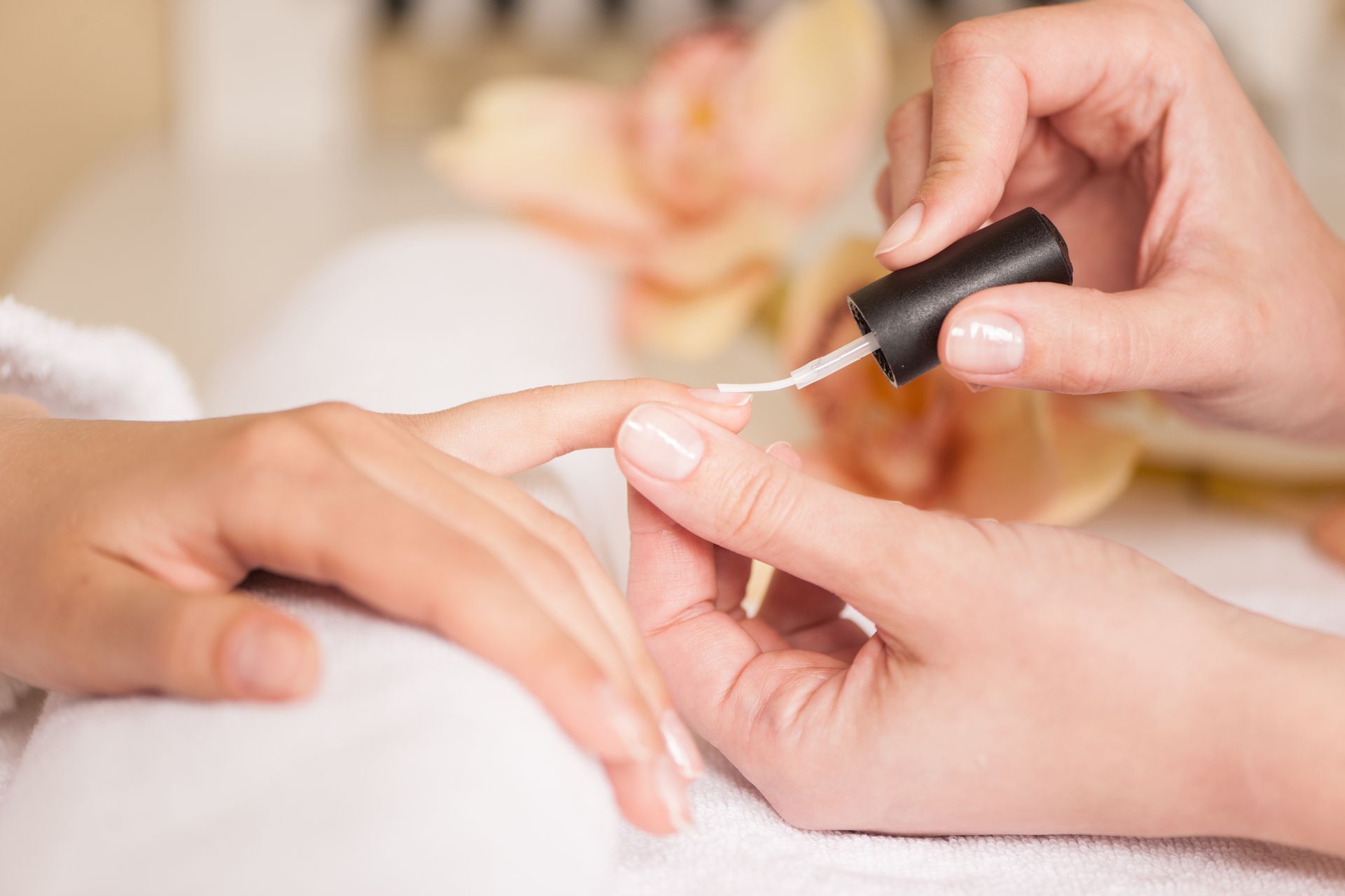 Woman in nail salon receiving manicure by beautician. closeup of female hand resting on white towel