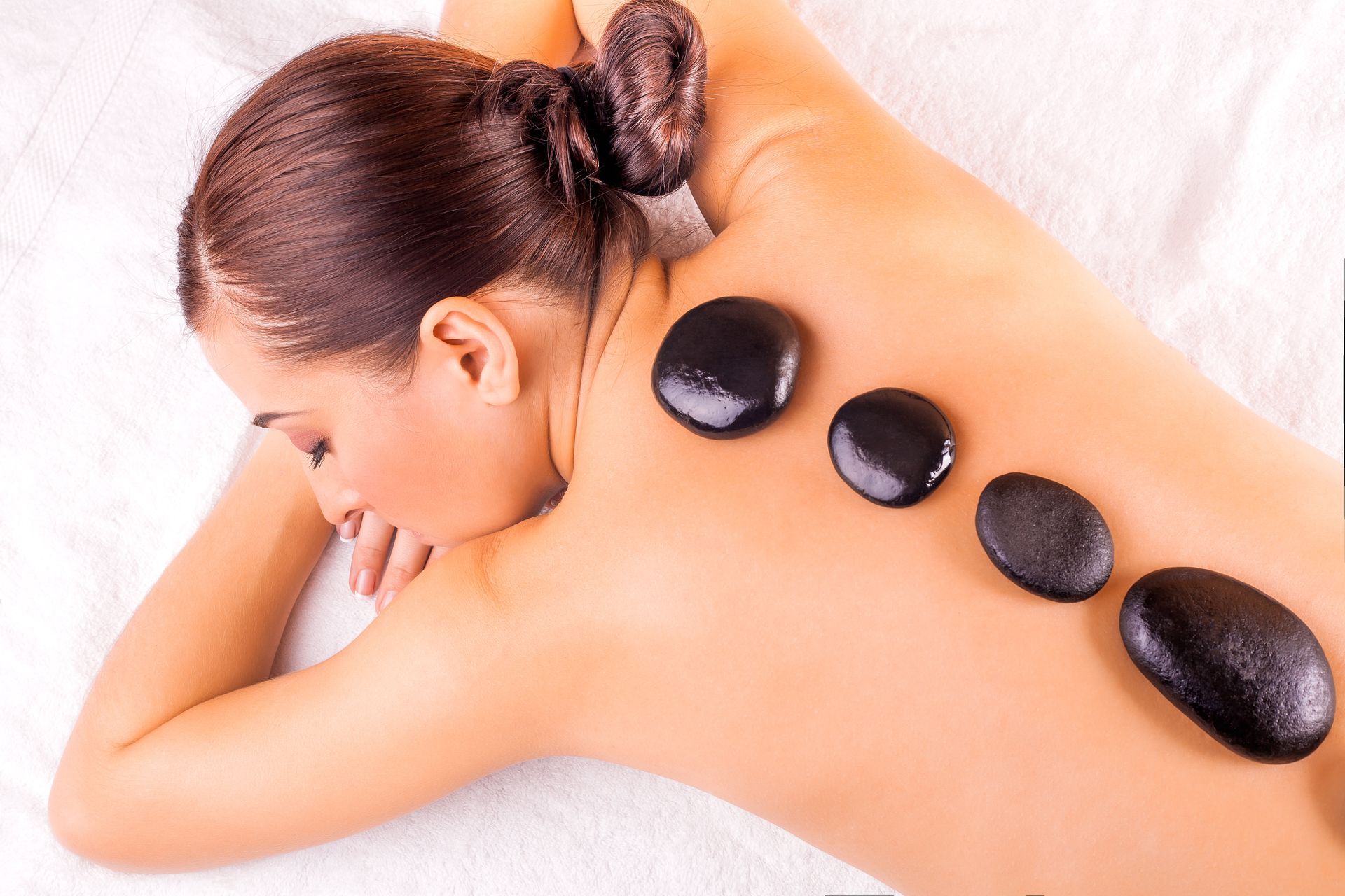 picture of woman in spa salon with hot stones.