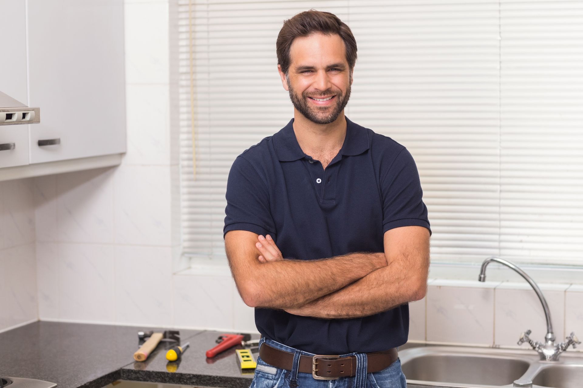 A man is standing in a kitchen with his arms crossed.