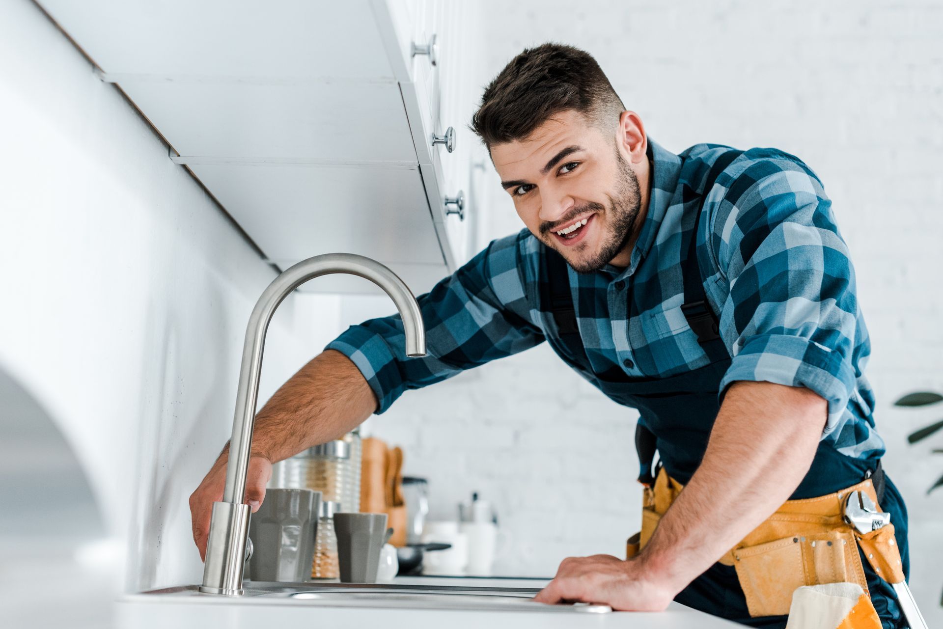 A man is fixing a faucet in a kitchen.