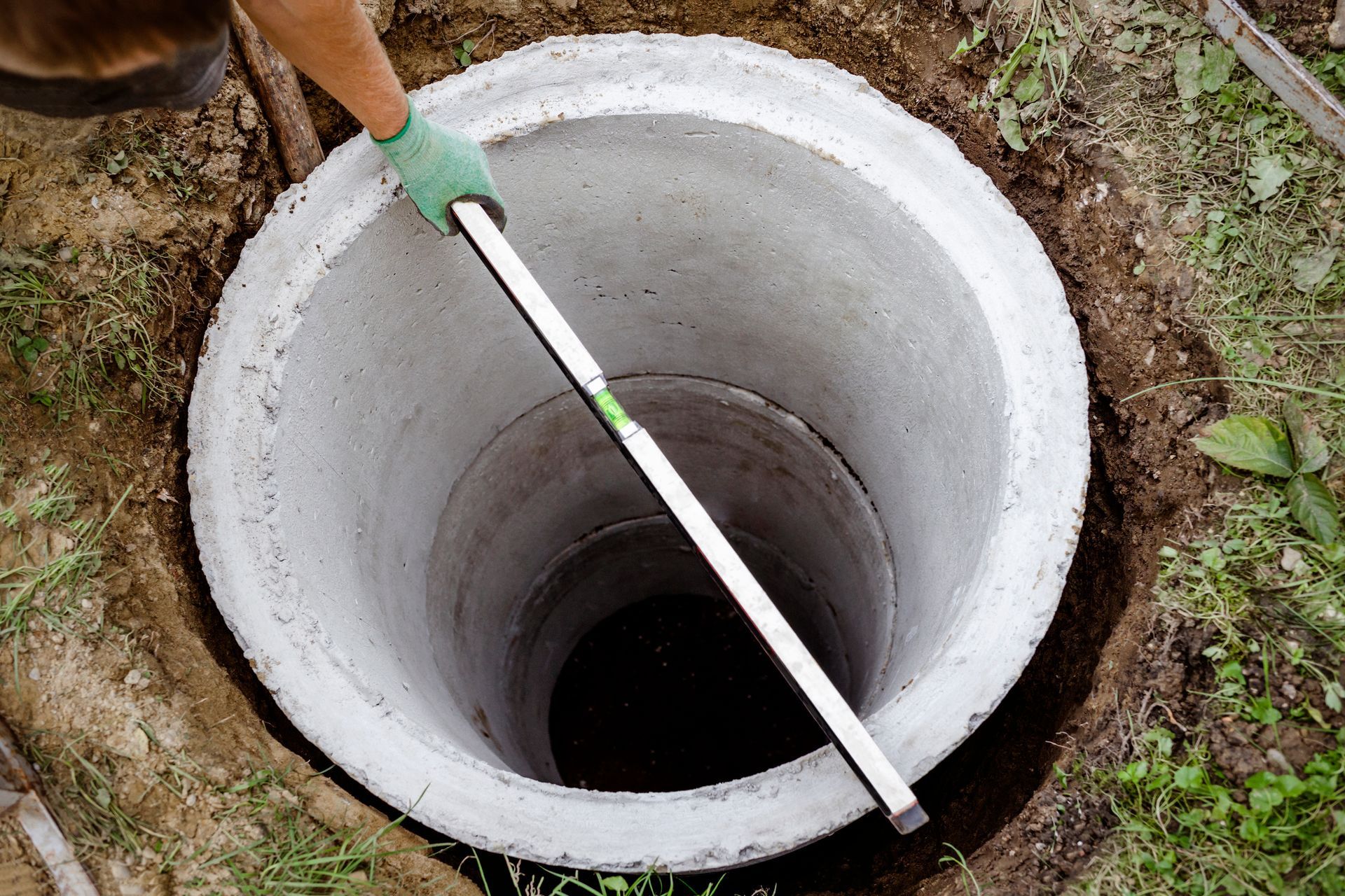 A person is measuring a concrete well with a level.