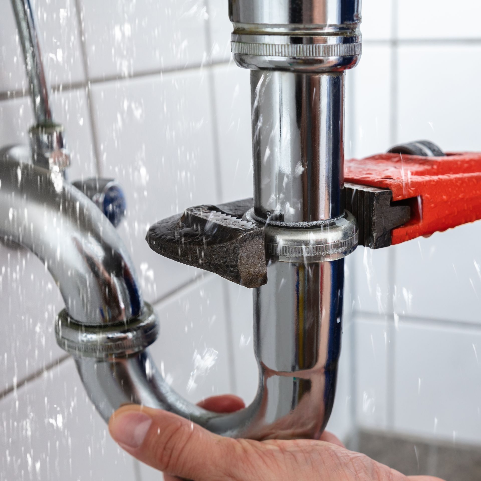 A person is fixing a sink pipe with a wrench.