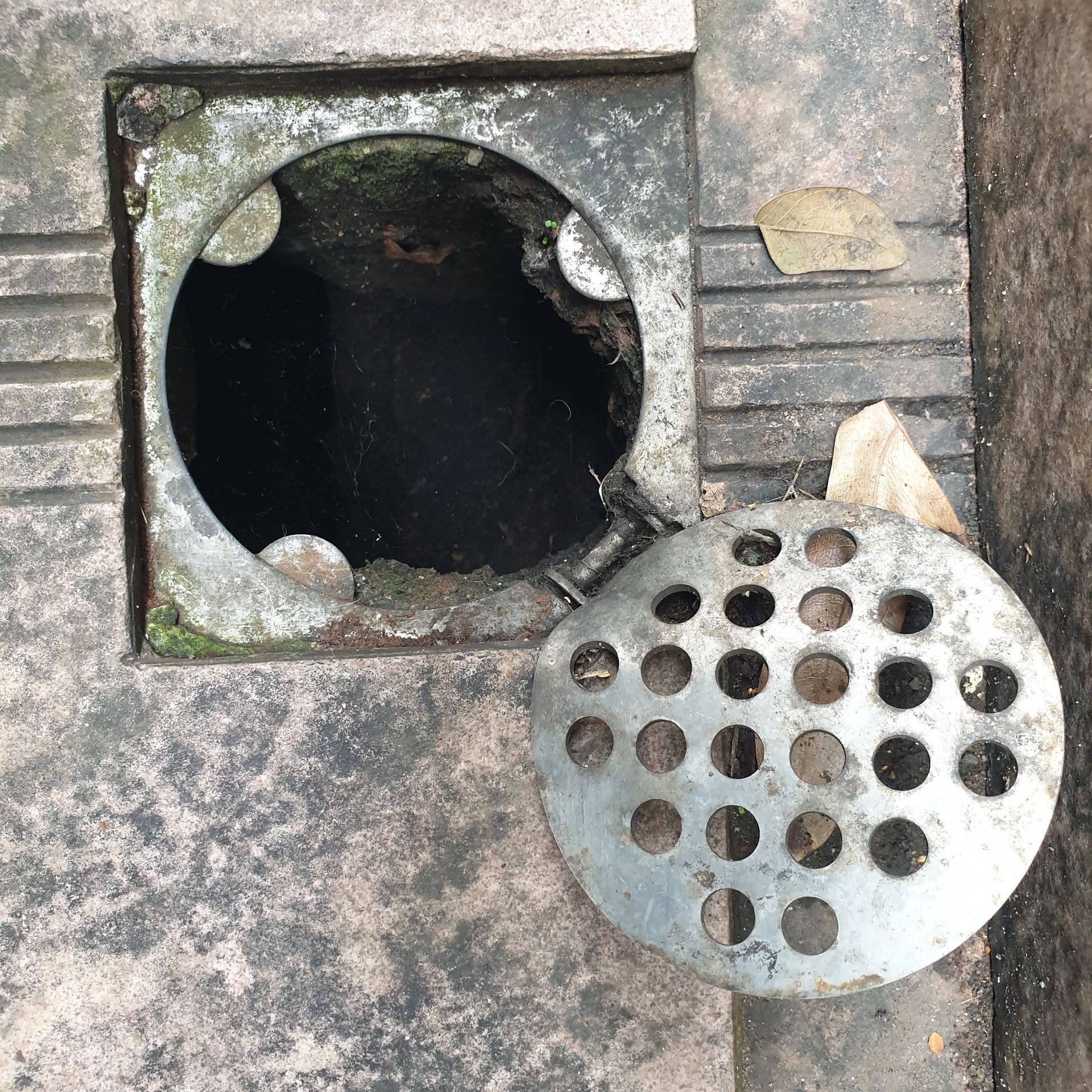 A drain with a hole in it and a drain cover on top of it.