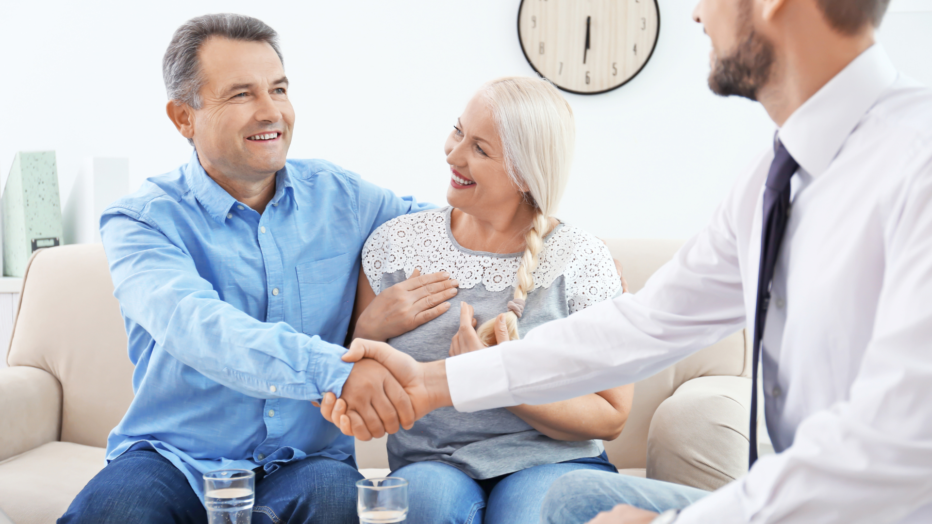 A man and woman are shaking hands with a doctor while sitting on a couch.