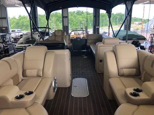 Interior view of a beige pontoon boat with seating, cup holders, and a wooden floor.