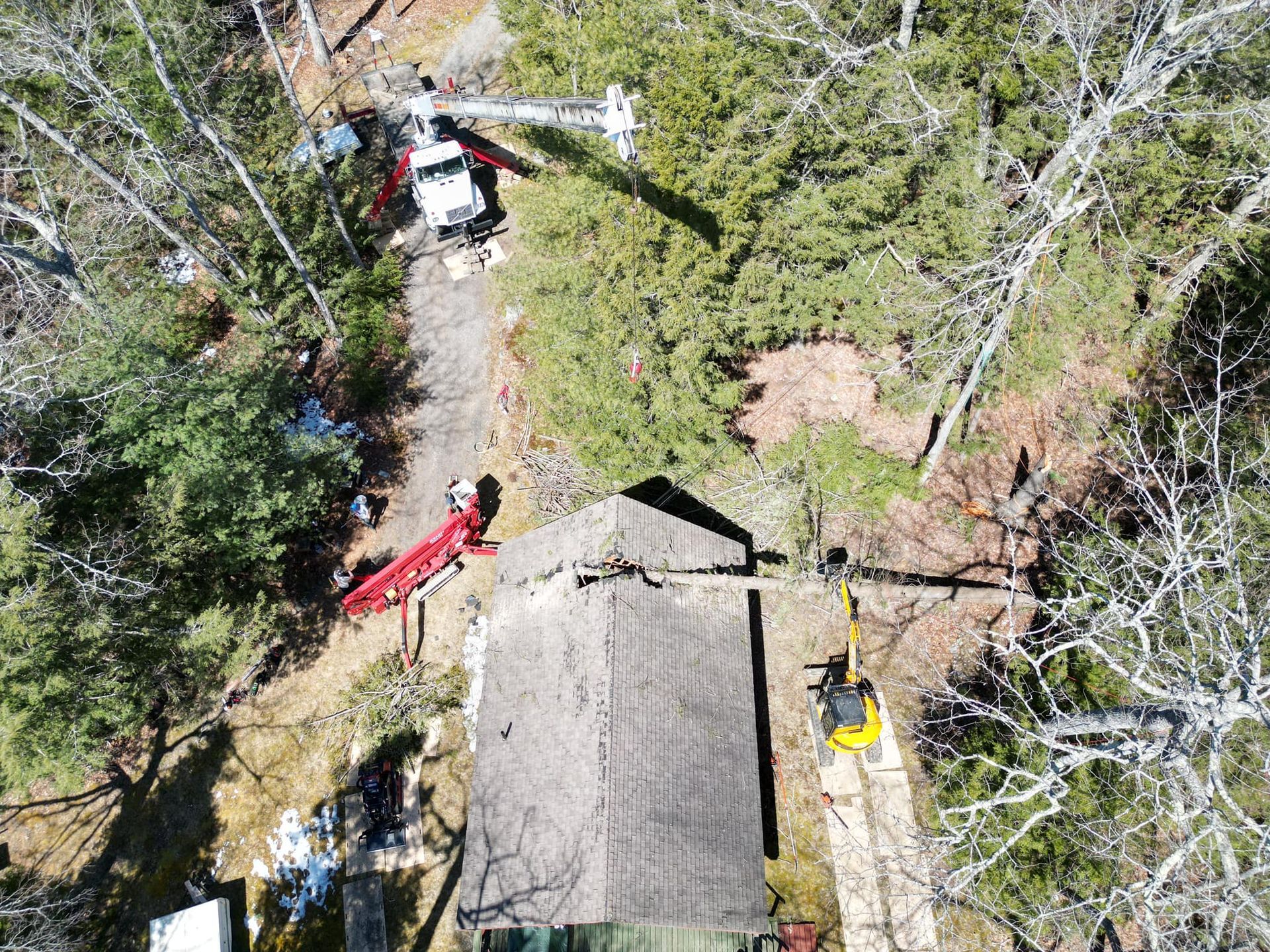 Aerial view: A red and white helicopter near a cabin in a wooded area.
