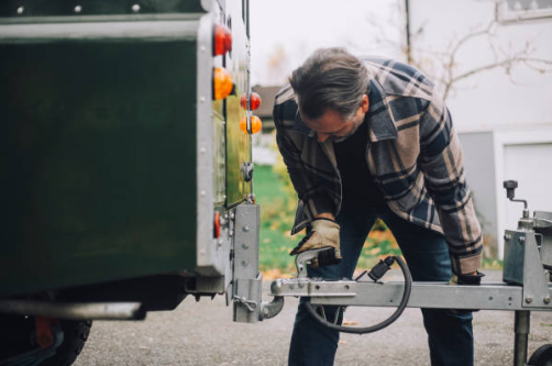 un uomo sta collegando un rimorchio a un veicolo .