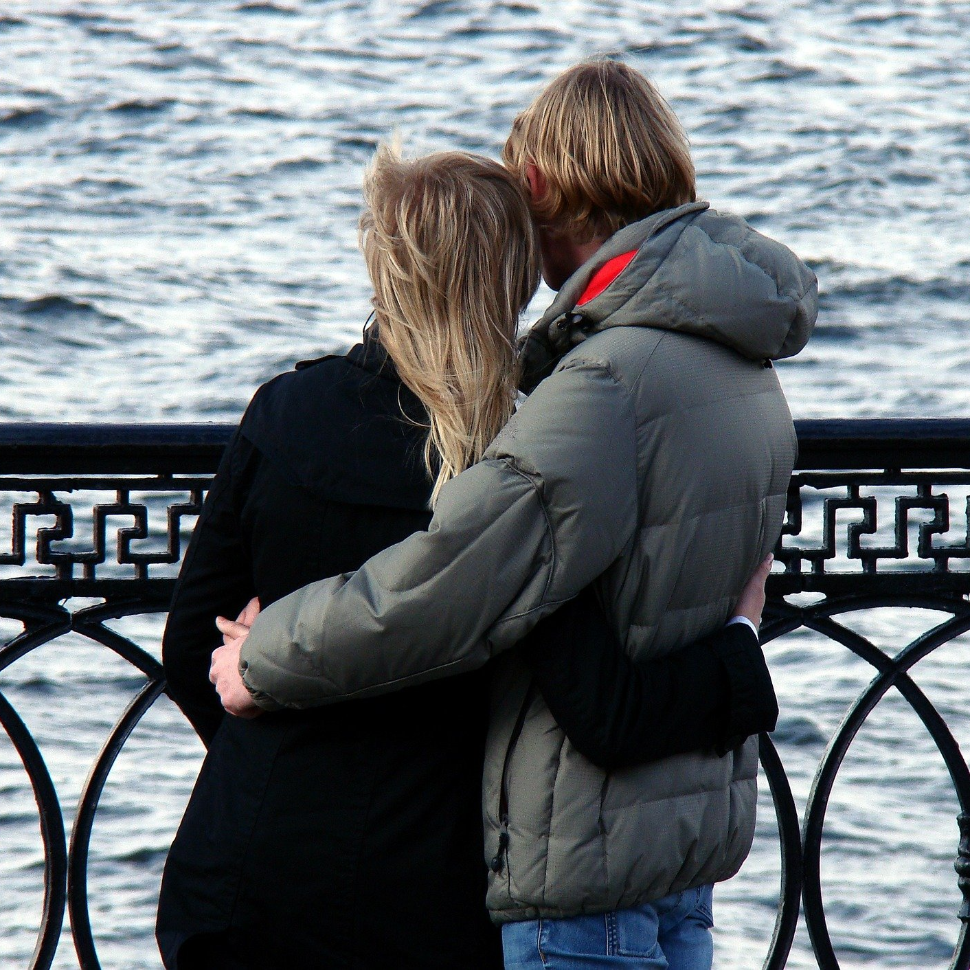 a couple standing together looking at a body of water.
