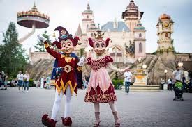 A couple of mascots standing next to each other in front of a castle.