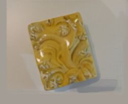 Azulejo cerámico rectangular de color amarillo y blanco con estampado floral.