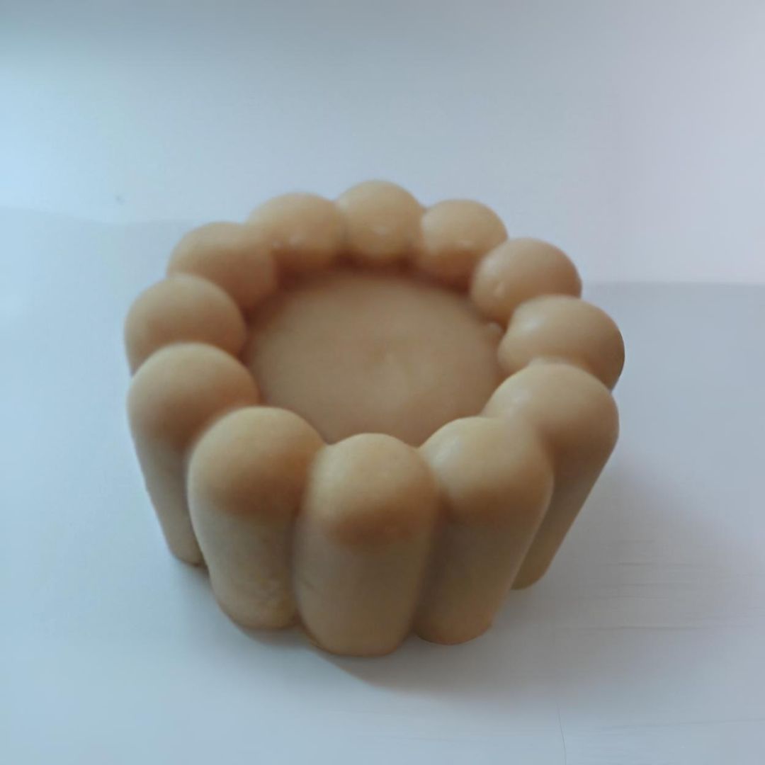 Jabón circular beige con diseño floral. El centro es hueco.