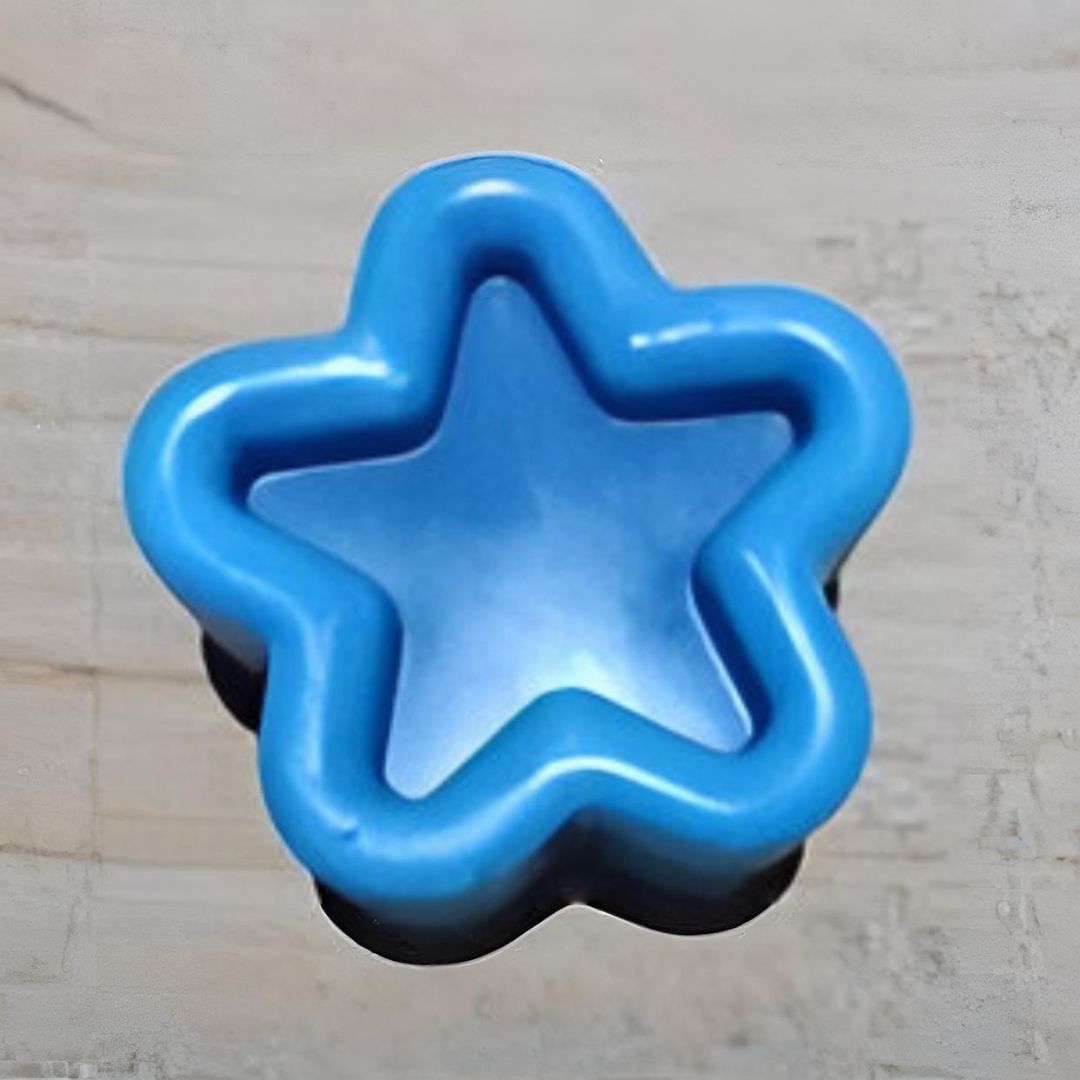 Cortador de gae unlletas de plástico azul en forma de estrella sobra superficie de madera.