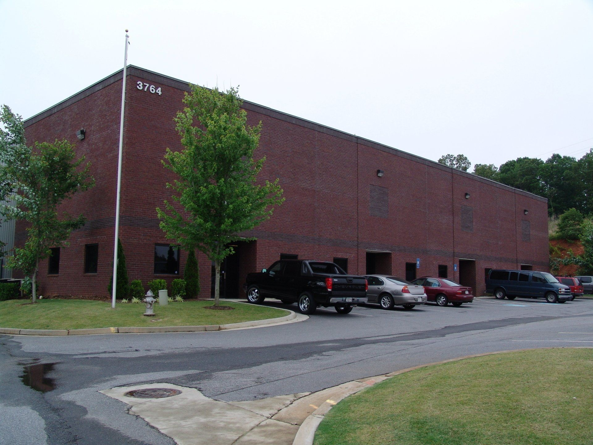 Red brick warehouse building with parked cars in front.