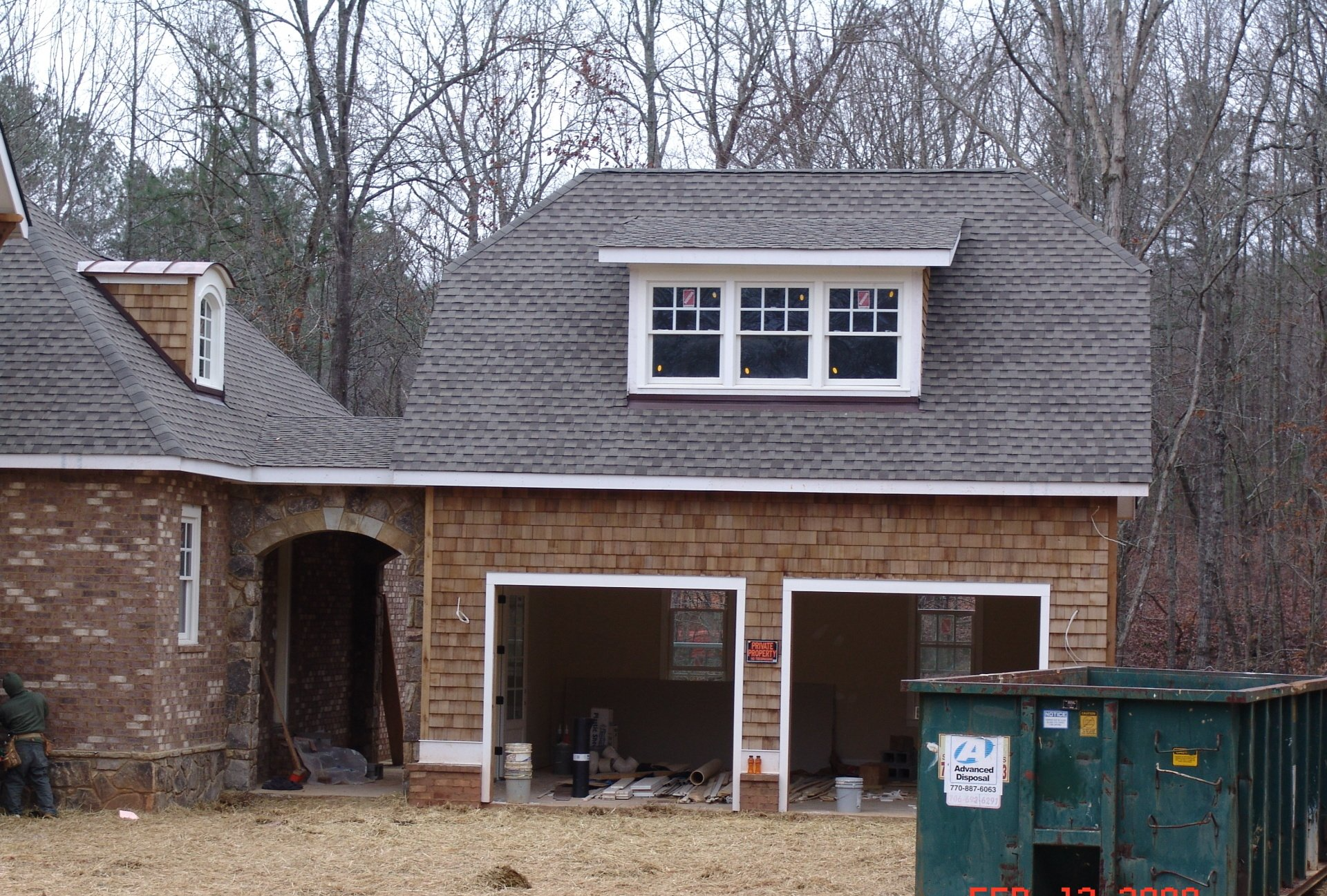 Garage under construction with two bays, brown siding, gray roof, and a window dormer.