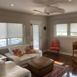 A living room with a couch , chairs , ottoman and a ceiling fan.