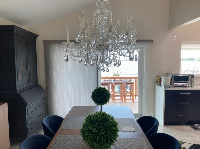 A dining room with a table and chairs and a chandelier hanging from the ceiling.