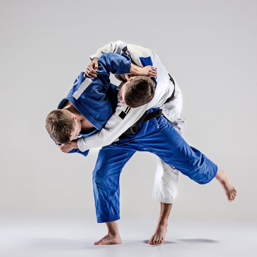 Group of children in martial arts attire posing, some with arms around each other, in a gym.
