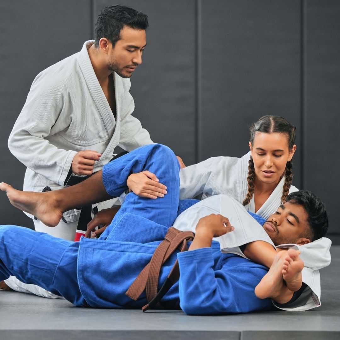 Two people practicing Brazilian Jiu-Jitsu on a mat. One is on top, applying a hold.