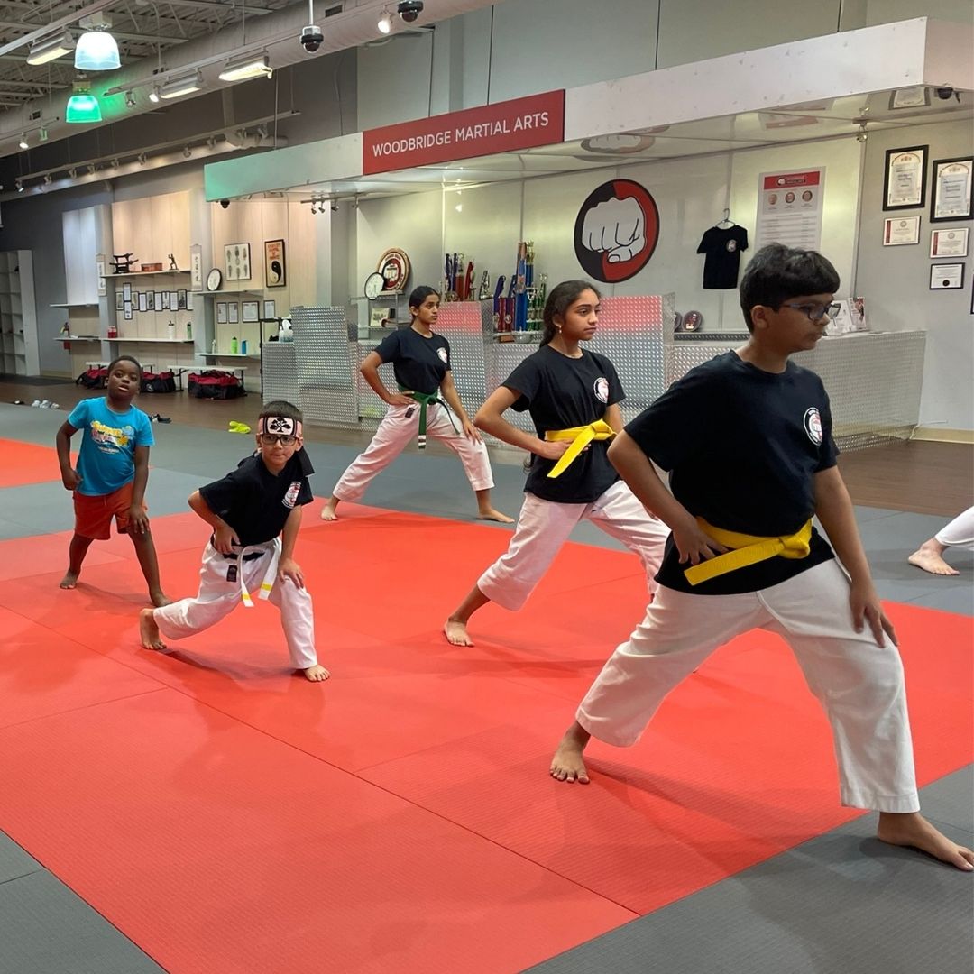 Two people grappling on a mat, one in a black gi, the other in a rash guard, legs entangled.