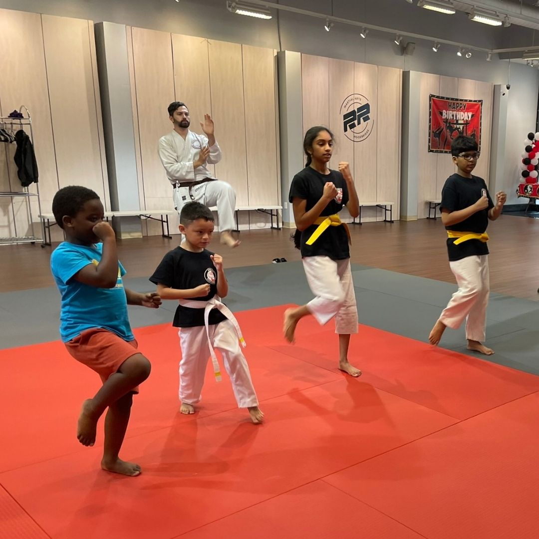 Two children grappling on a mat, one in a headlock.