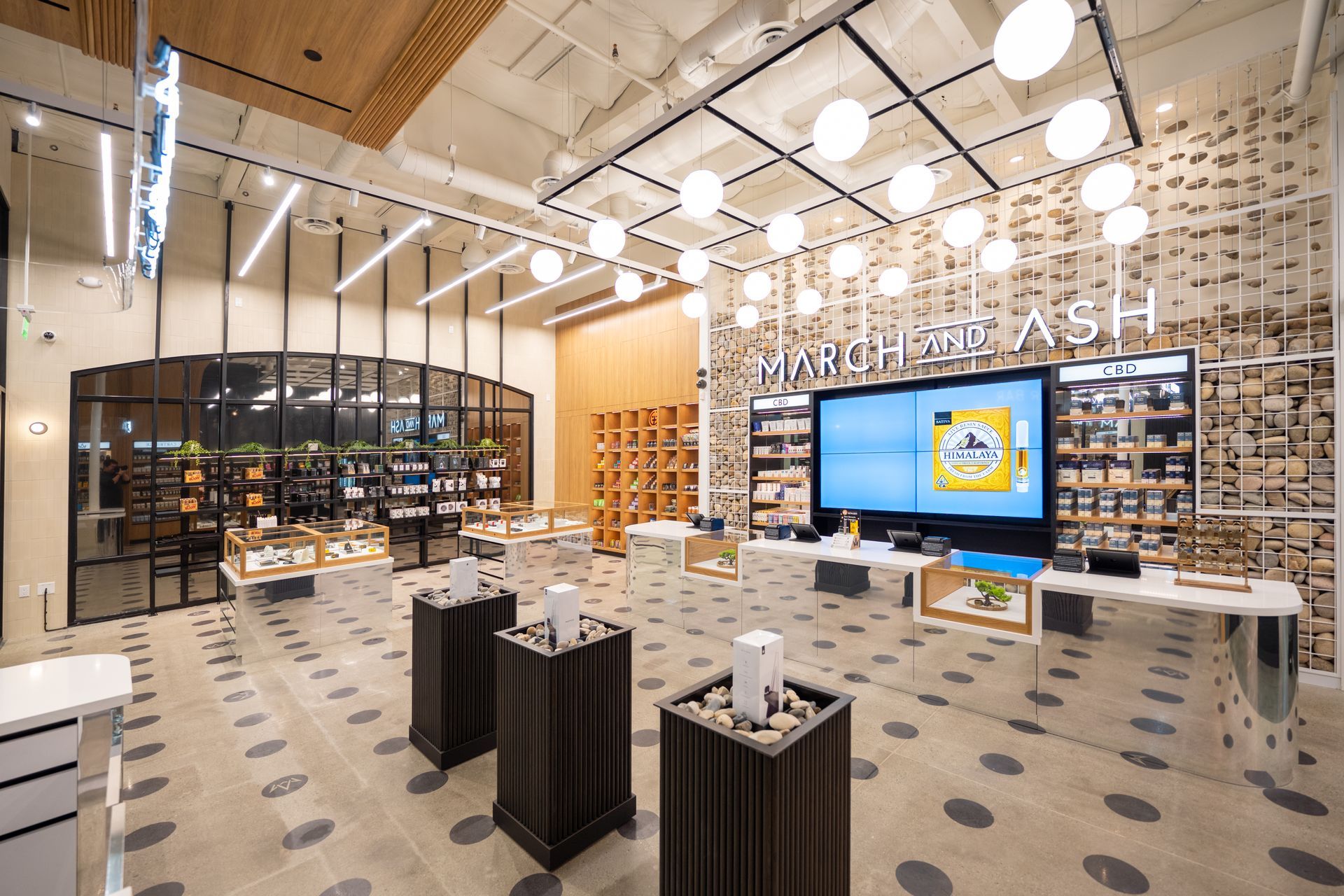 Interior of a brightly lit shop with displays, a large screen, and decorative shelving.
