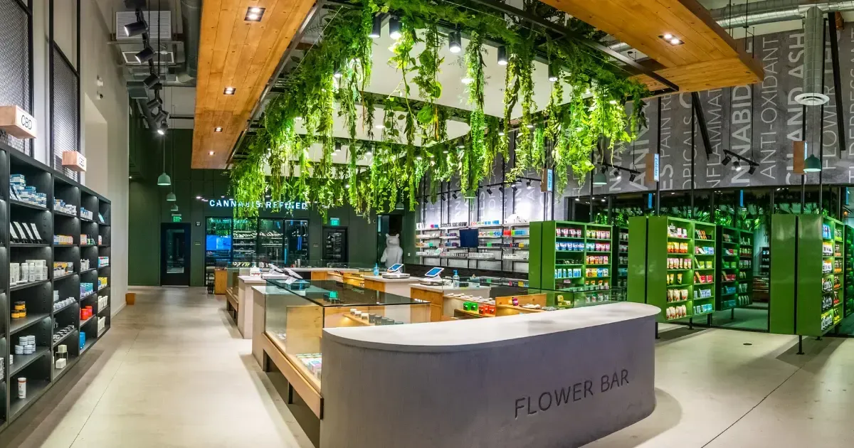 Cannabis dispensary interior with green plants, product displays, and a curved counter.