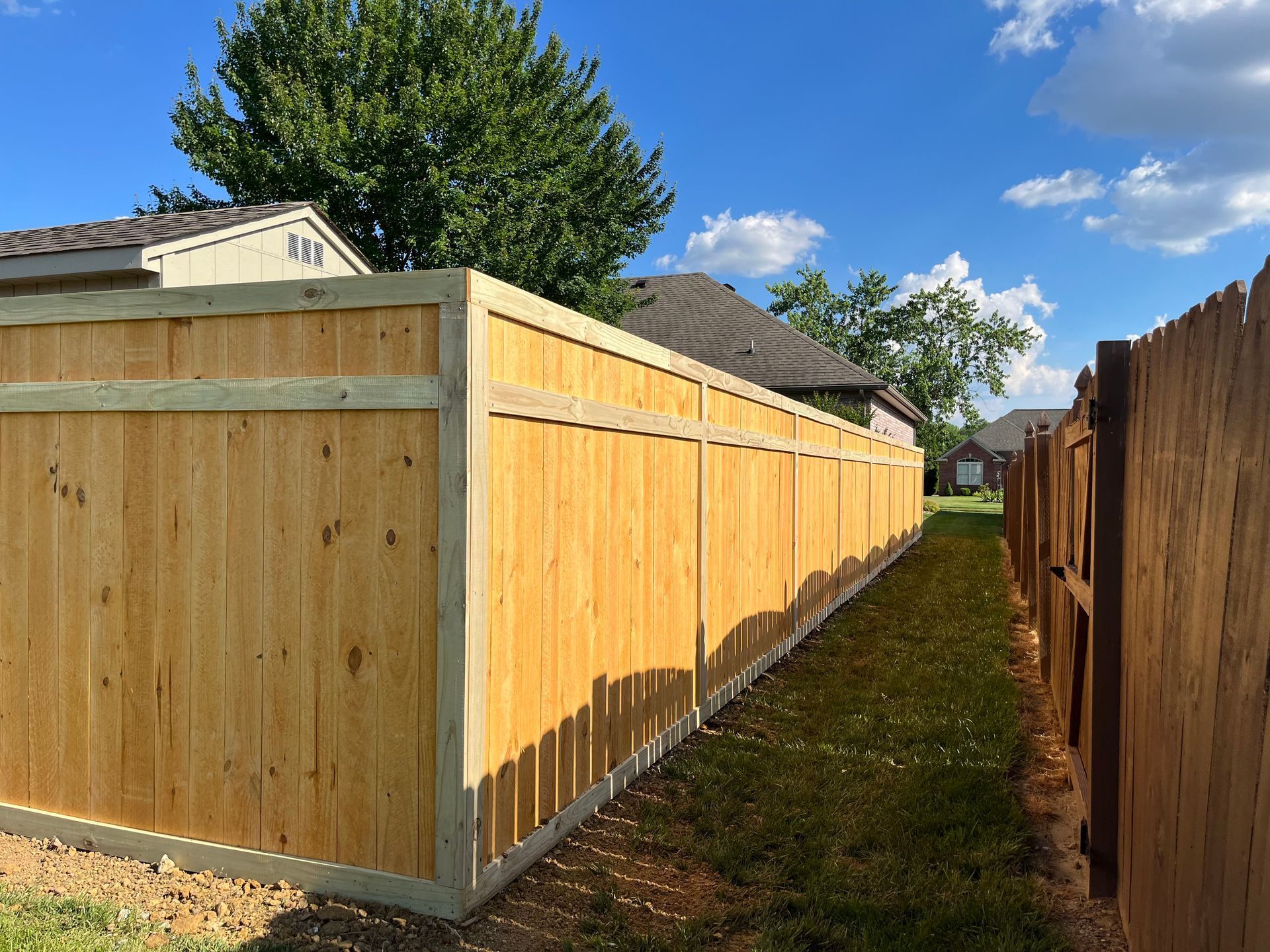 A wooden fence with a gate in the backyard of a house.
