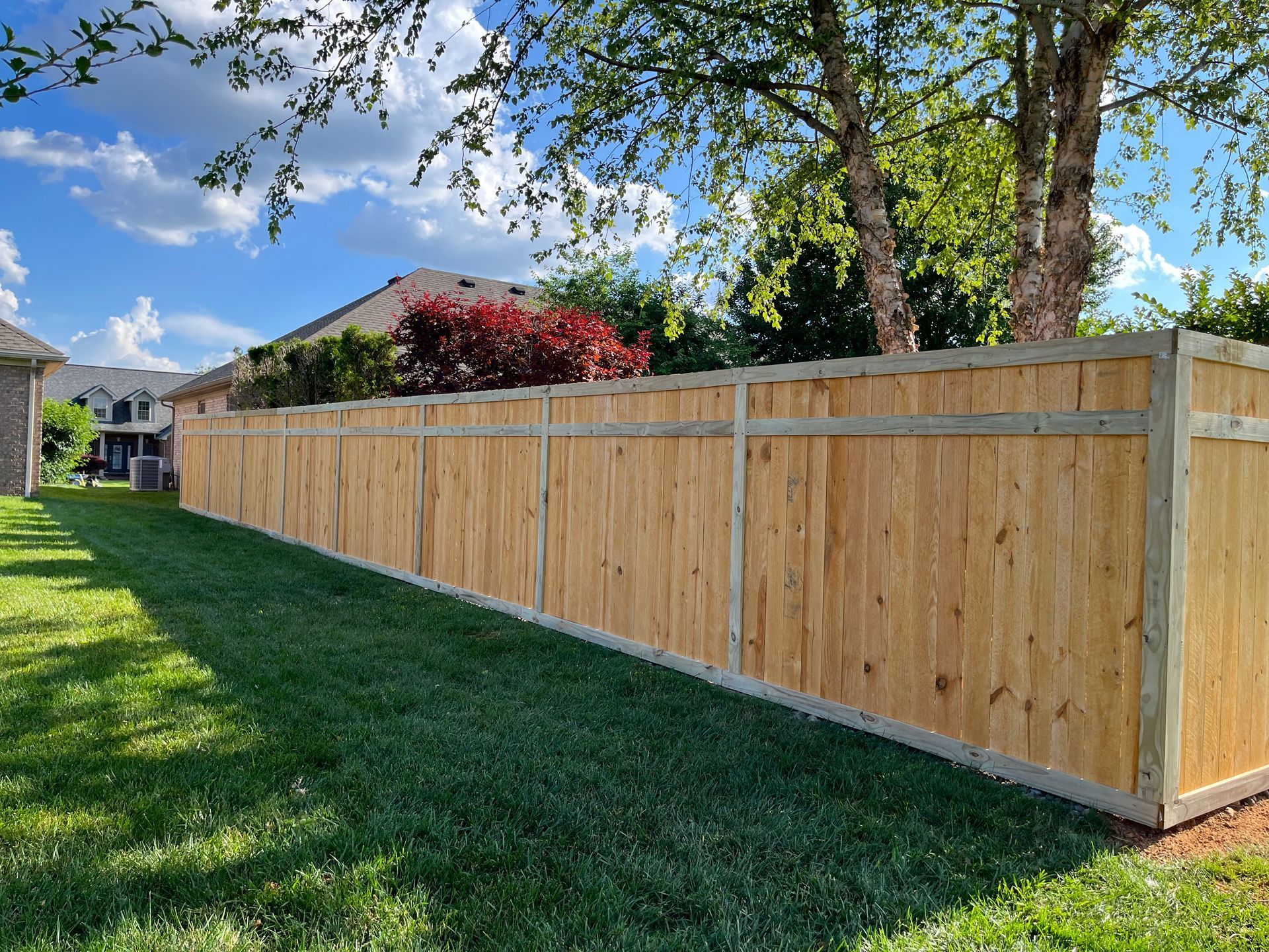 A wooden fence is sitting in the middle of a lush green yard.