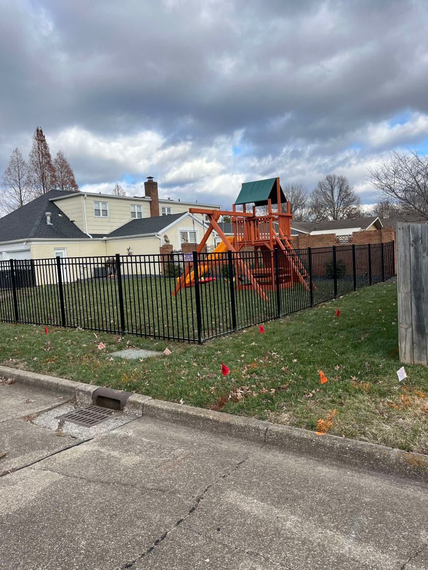 There is a playground in the backyard of a house behind a fence.