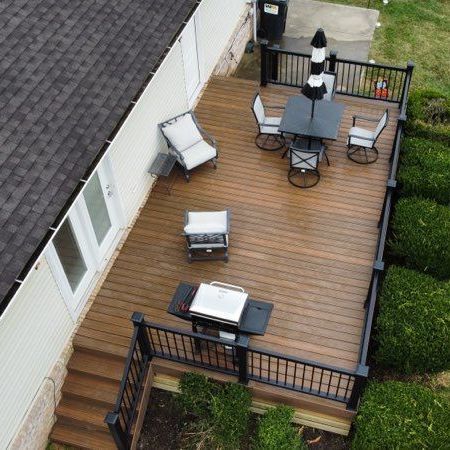 An aerial view of a wooden deck with a table and chairs and a grill.