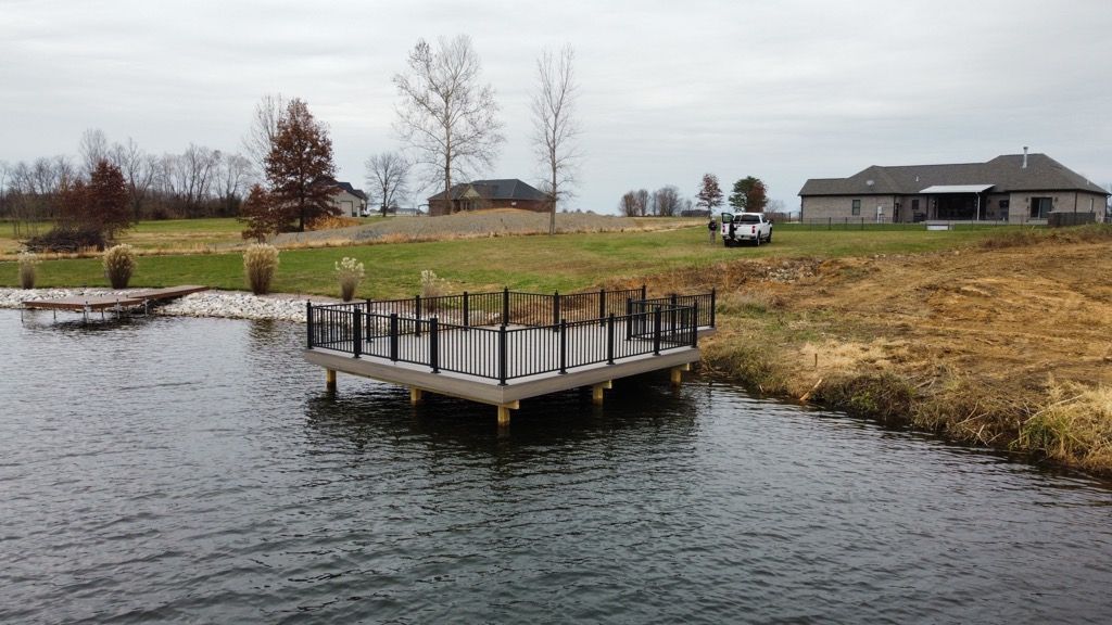 A dock in the middle of a lake with a house in the background