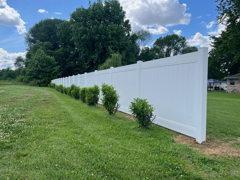 A white fence surrounds a lush green field.