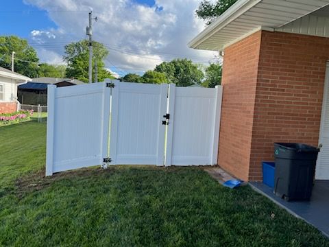 A white fence is sitting in front of a brick house.