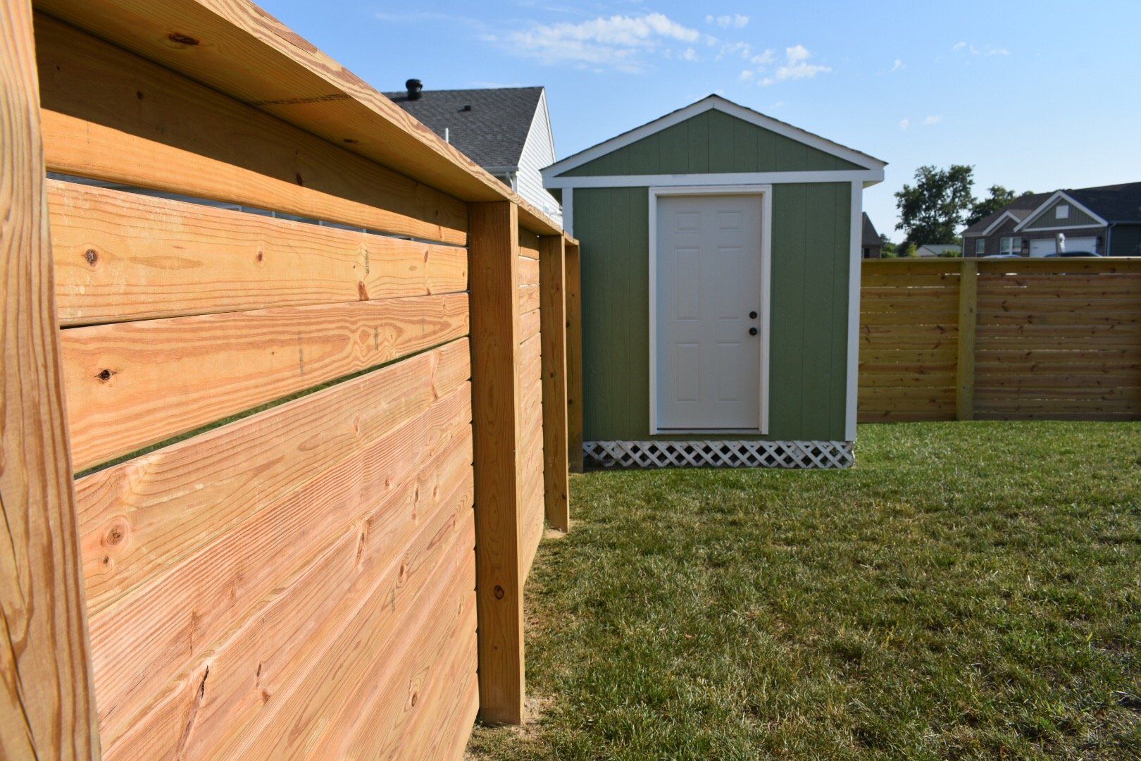 Wooden fenced in yard with green shed in the back corner
