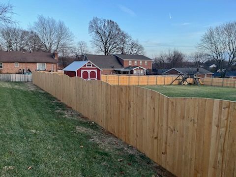 A wooden fence surrounds a yard with a red barn in the background.