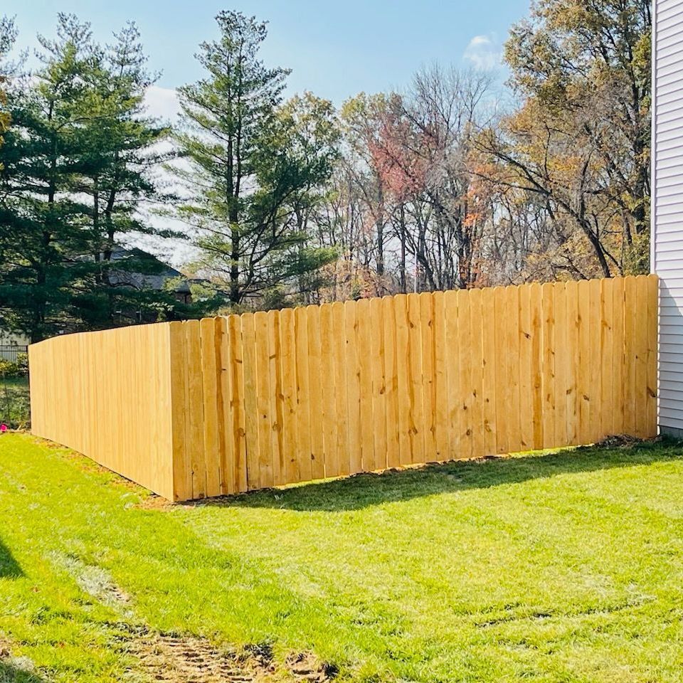A wooden fence is in the backyard of a house.