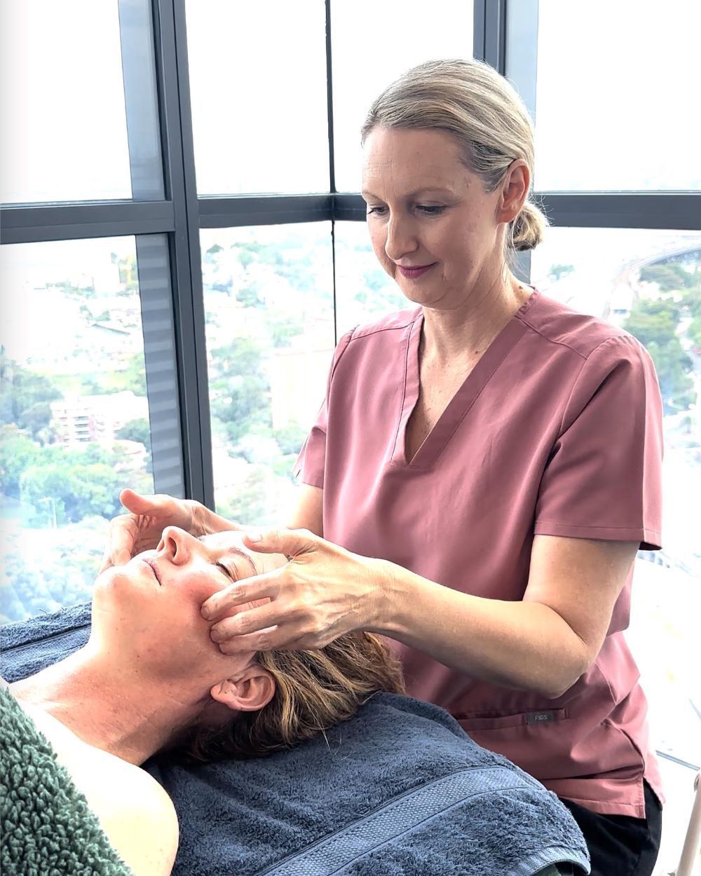 A Woman is Giving a Woman a Facial Massage in Front of a Window — Organic Beauty by Kessie in Yeppoon, QLD