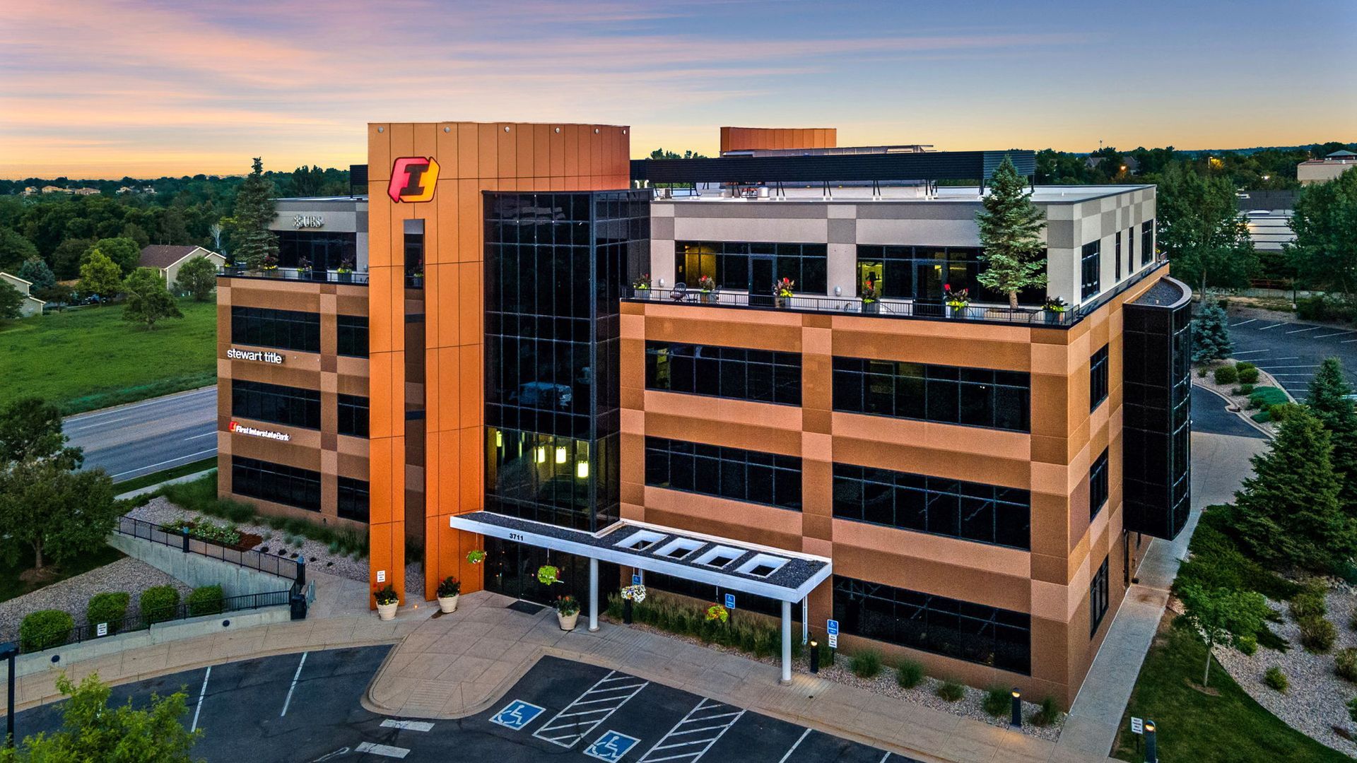 An aerial view of a large brick building with a parking lot in front of it.