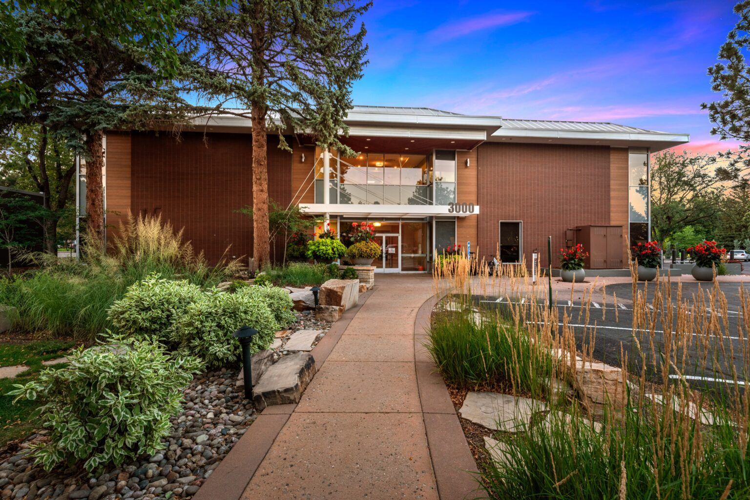 A large brick building with a walkway leading to it and a pond in front of it.