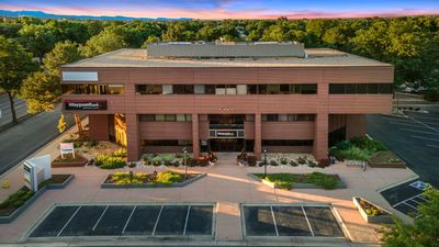 An aerial view of a large brick building with a parking lot in front of it.