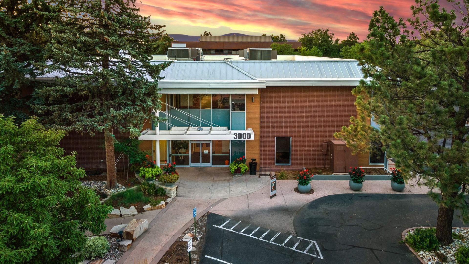 An aerial view of a large brick building with a parking lot in front of it.