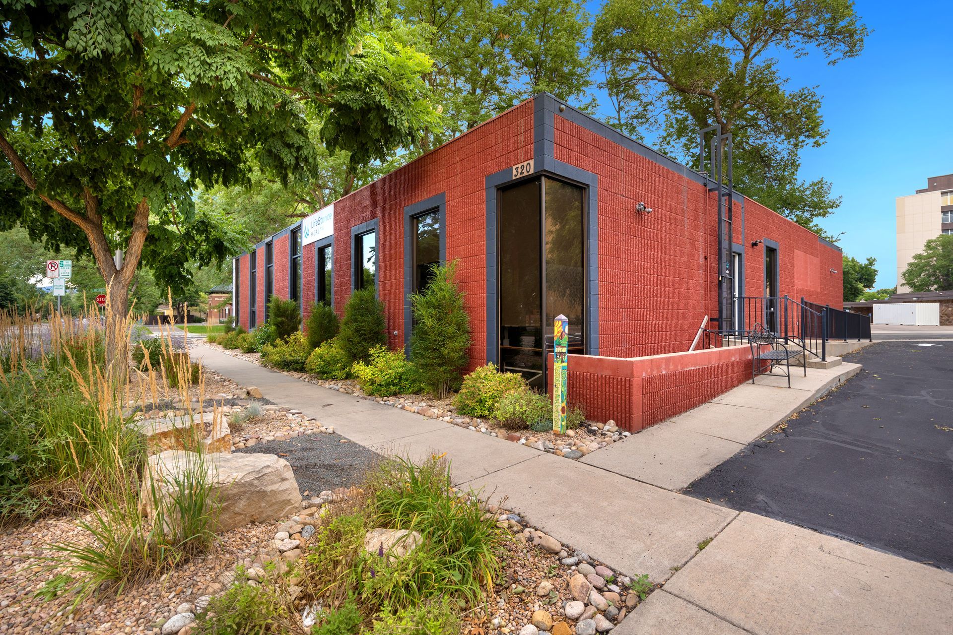 A red brick building with a sidewalk and trees in front of it.