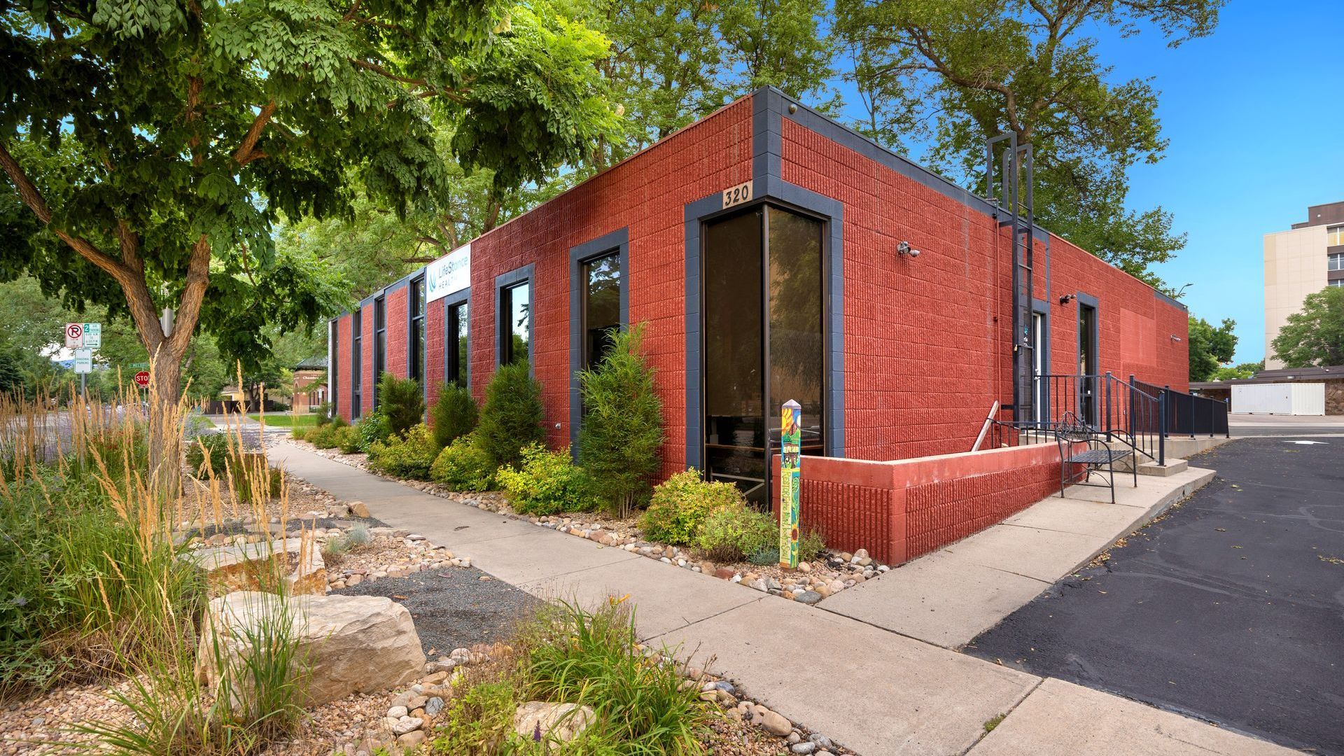 A red brick building with a sidewalk and trees in front of it.