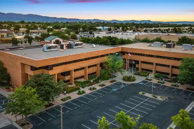 An aerial view of a large brick building with a parking lot in front of it.