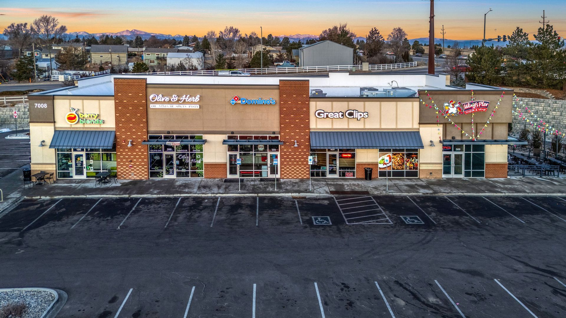 A home office with blue walls , a desk , chairs , shelves and a laptop on it.