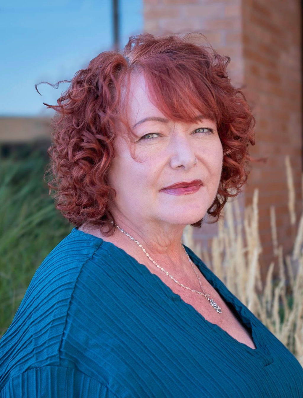 A woman in a green dress is smiling for the camera.