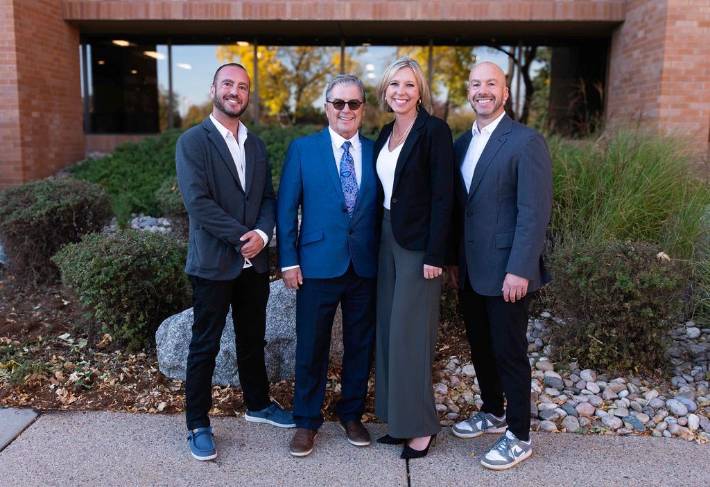 Three men in suits and ties are posing for a picture in front of a building.