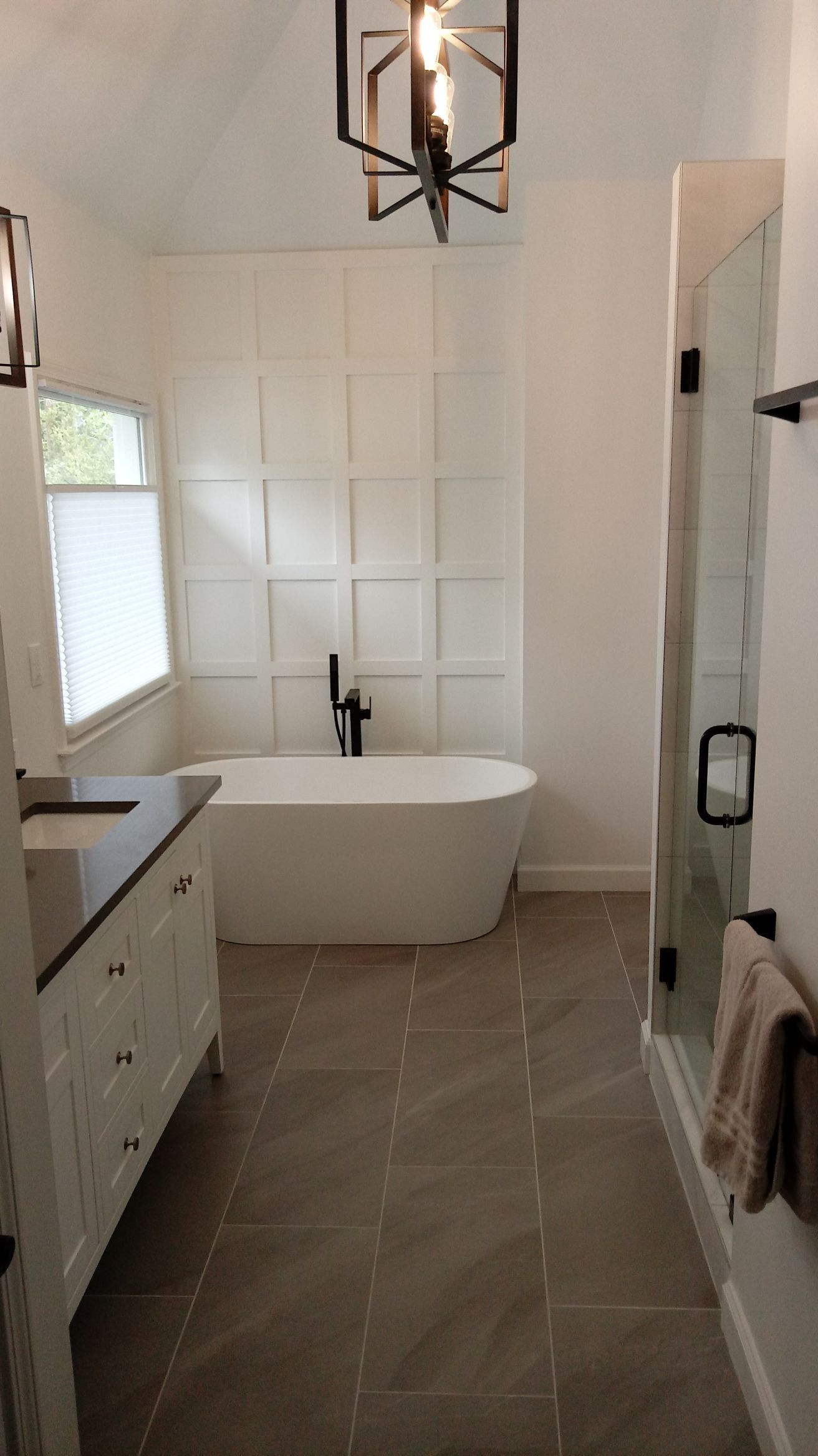 Bathroom with white walls, a standalone tub, and glass shower.
